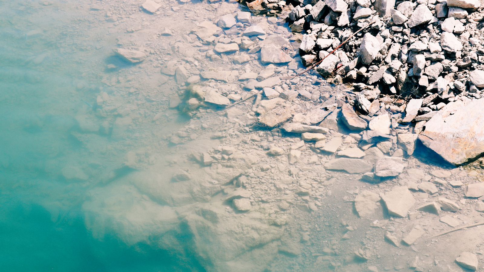 A serene rocky shoreline contrasting with clear turquoise water in Samsun, Türkiye.
