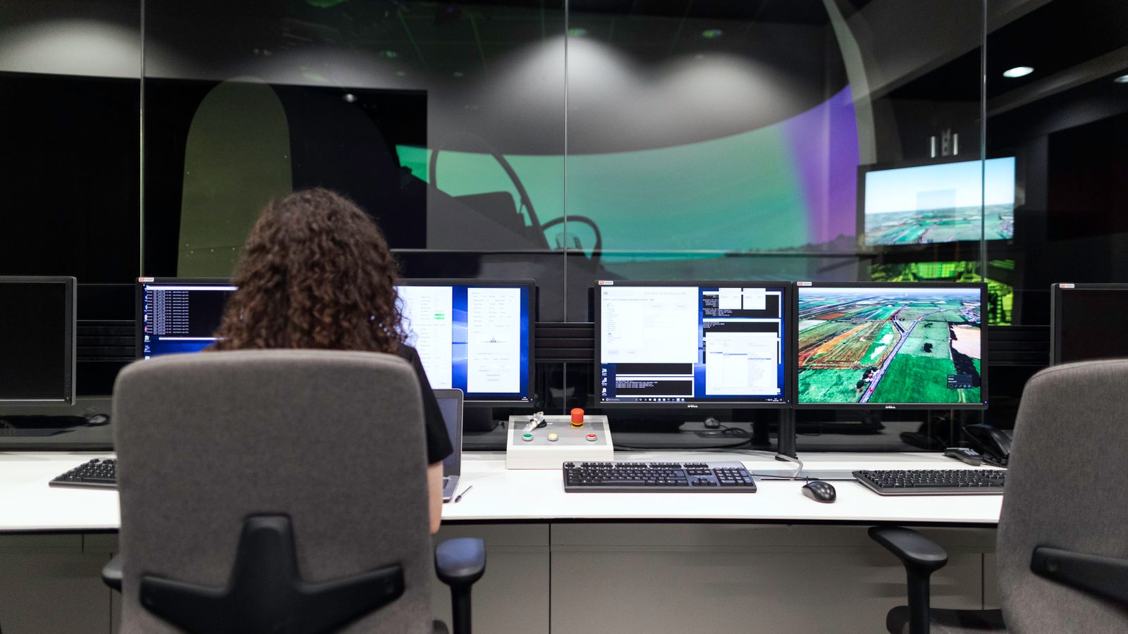 Female engineer managing multiple screens during a technology simulation in a control room.