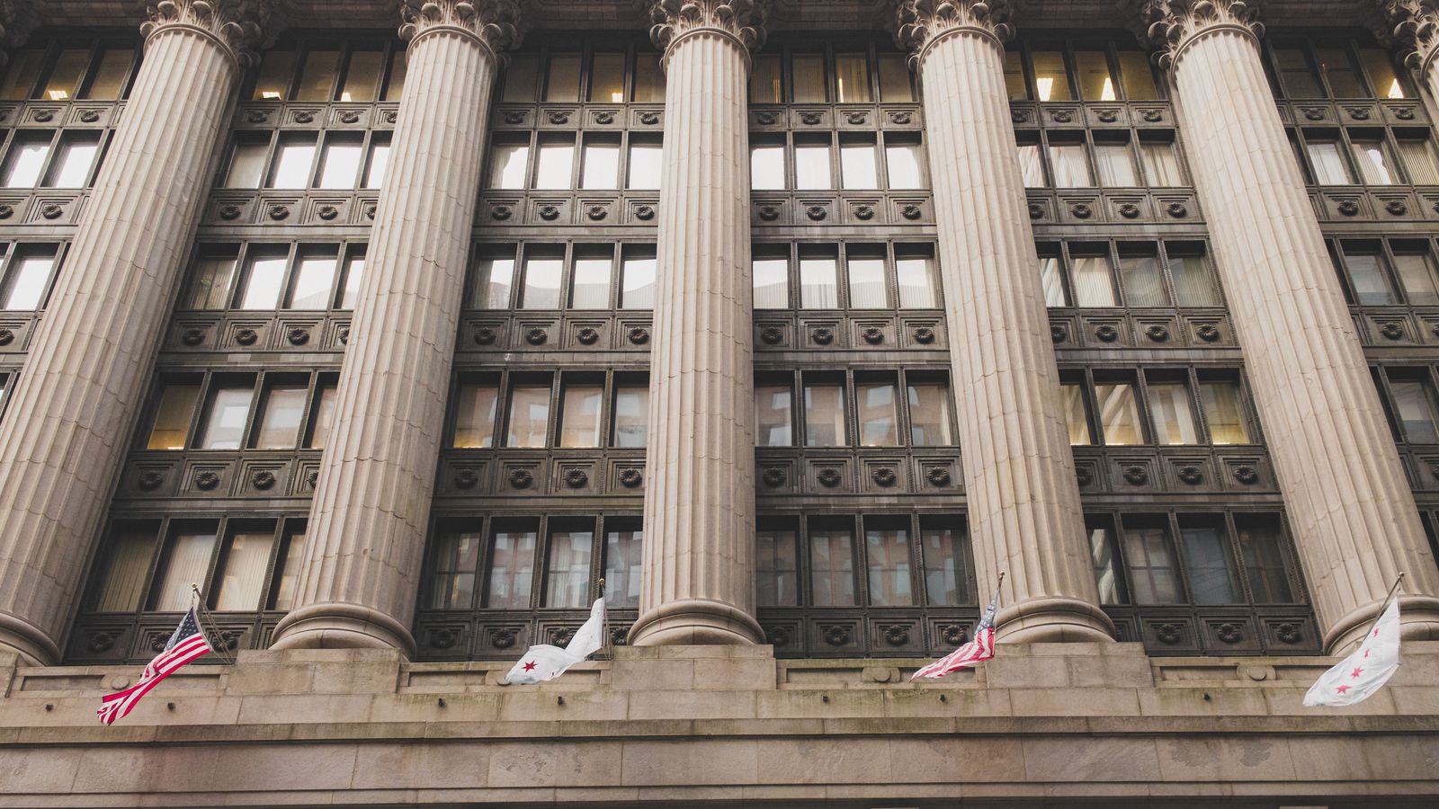 Elegant neoclassical facade with columns and flags in downtown Chicago.