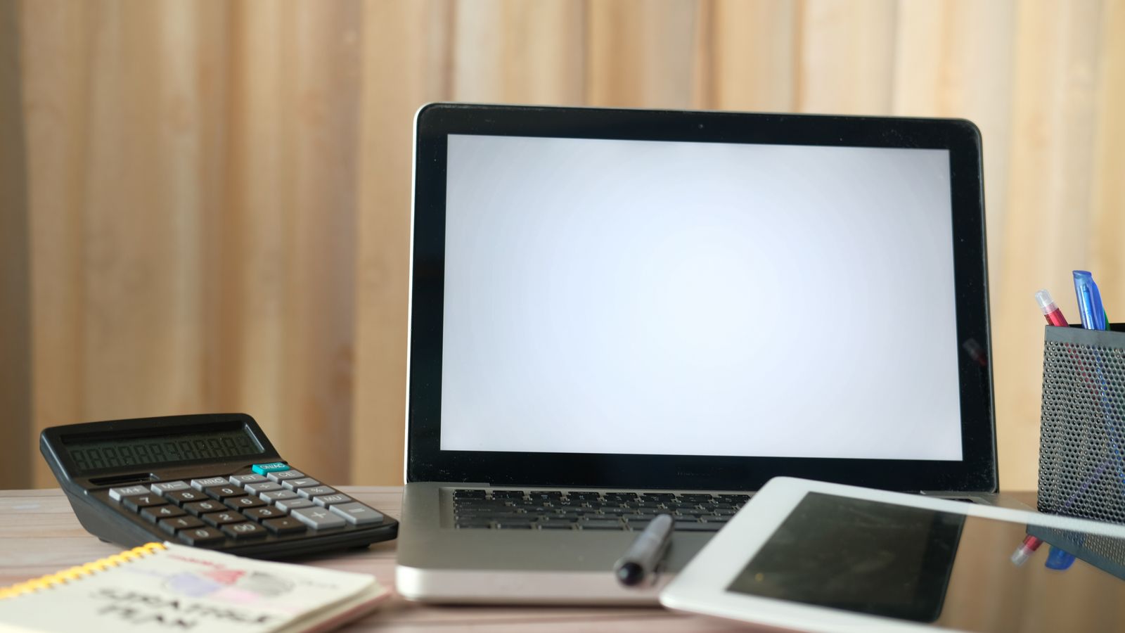 Organized office desk with a laptop, calculator, and tablet ready for business tasks.