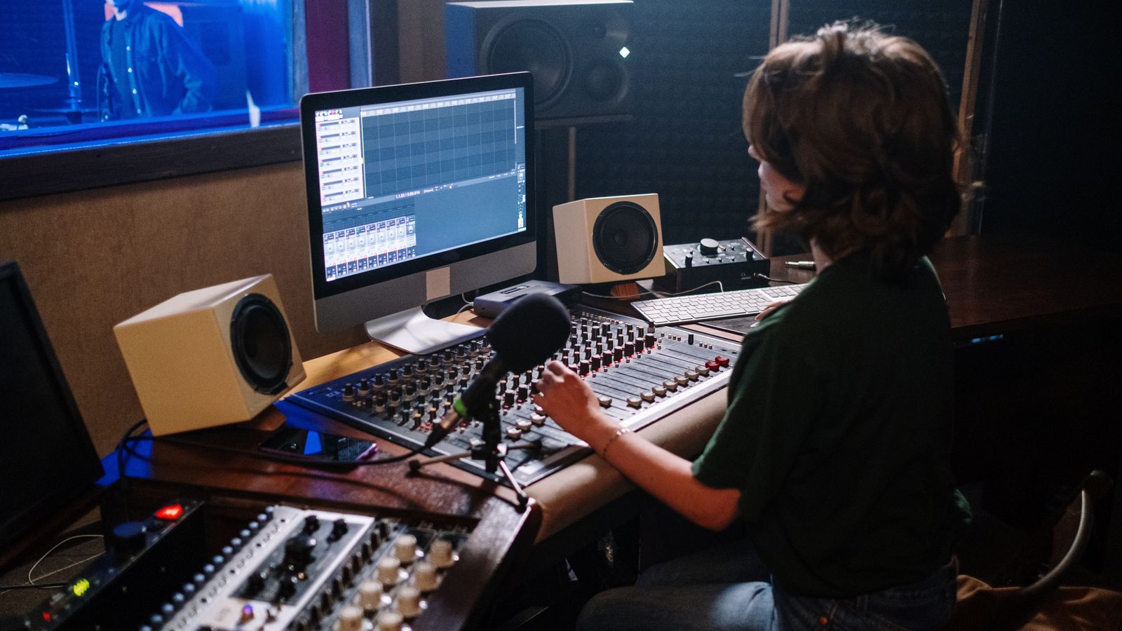 Sound engineer working at a modern recording studio with mixing equipment and computer.