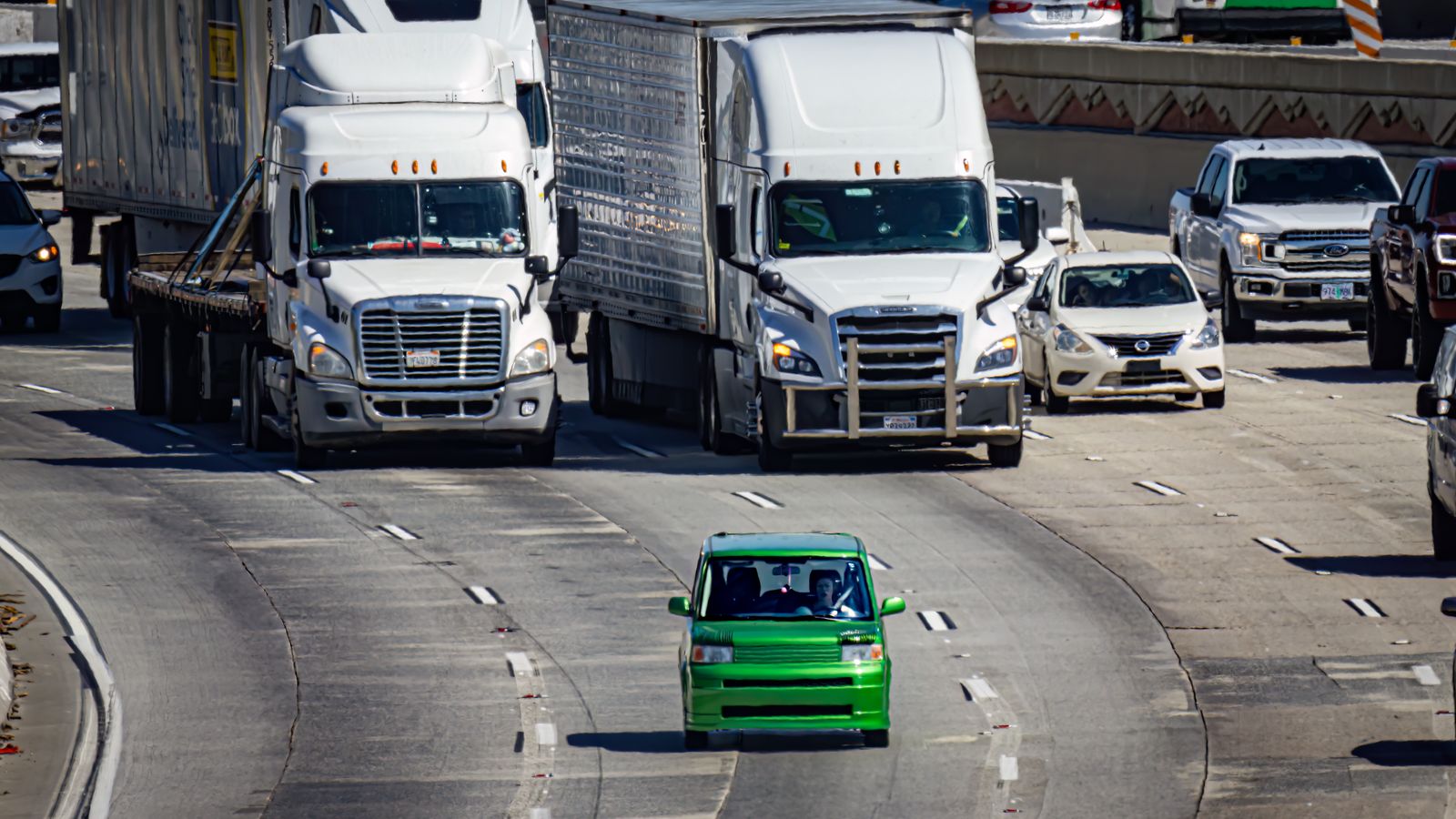 Aerial view of a bustling highway with cars and trucks in urban traffic.
